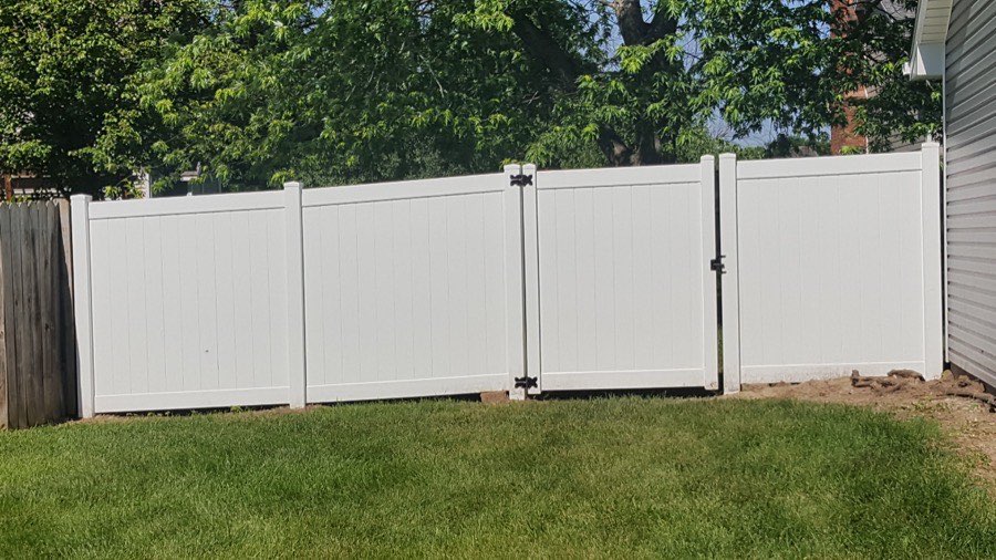 White vinyl privacy fence with gate installed in a backyard