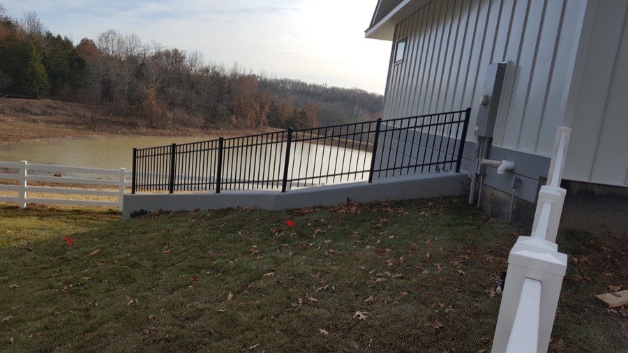 Black aluminum fence overlooking a pond behind a home
