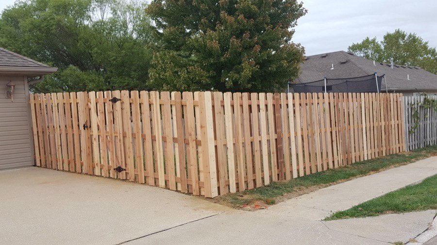 Cedar shadowbox style wood privacy fence along a driveway