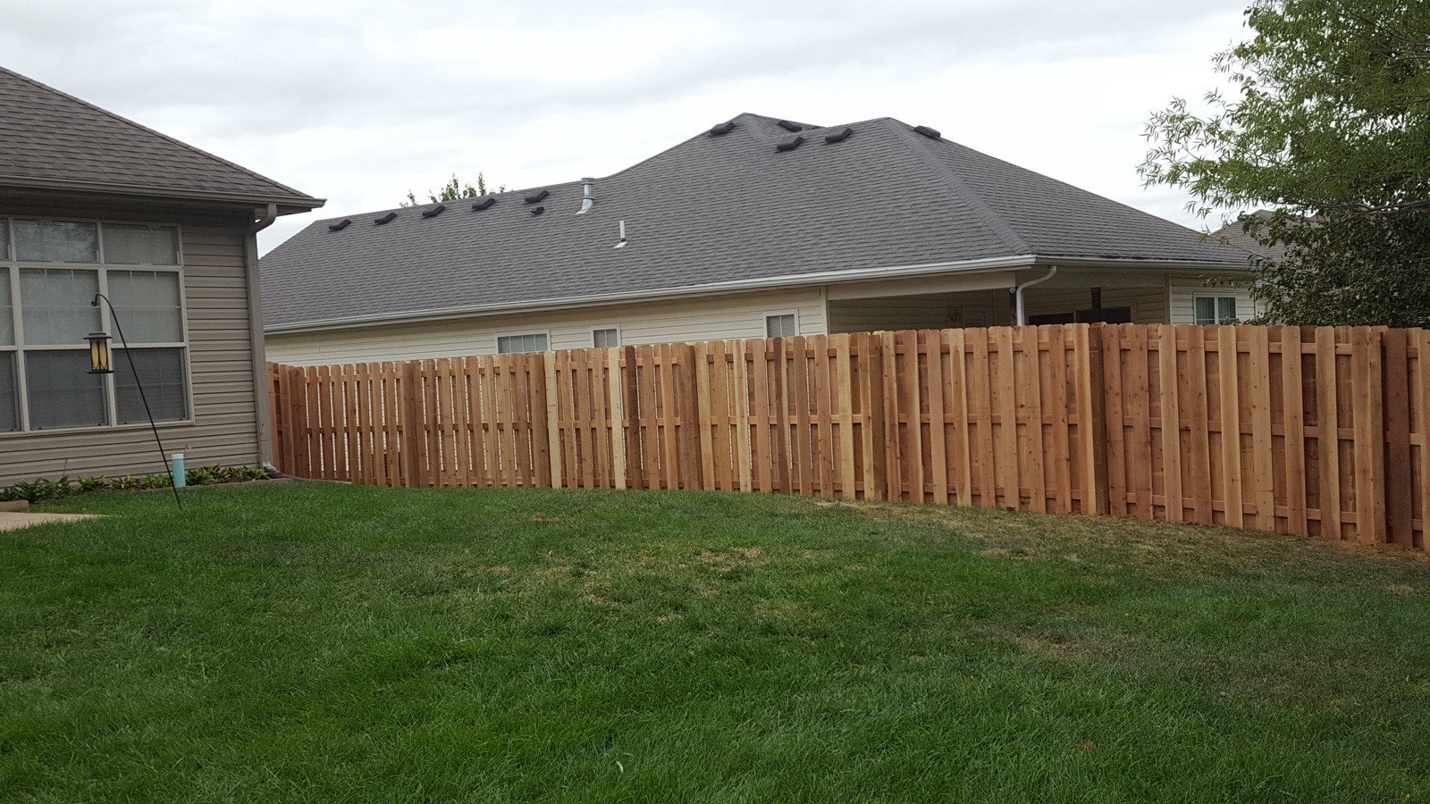 Cedar wood privacy fence installed along a backyard tree line in Columbia, MO